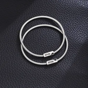 Stainless steel spring couple bracelet detail shot, elegant silver metal design with love charm.