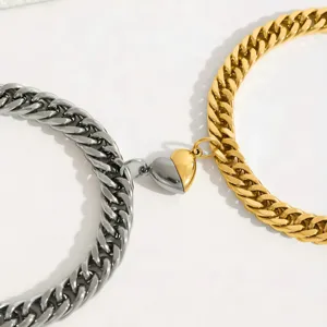 Stainless steel Cuban link bracelet detail with magnetic heart clasp in silver and gold.