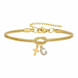 Dettaglio di bracciale a catena serpente dorata con nodo d'amore, croce e ciondolo lettera C.