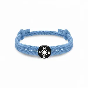 Hellblaue geflochtene Seil Armband Detail mit schwarzem Kompass Charme, minimalistischer Schmuck.