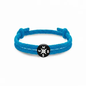 Blaues geflochtenes Seilarmband mit einem schwarz-weißen Kompass-Anhänger als Detail.