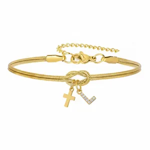 Dettaglio del bracciale a catena serpente dorata con nodo d'amore, croce e ciondolo con strass.