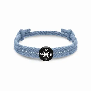 Blaues geflochtenes Seilarmband mit schwarzem runden Kompassanhänger und Buchstaben.