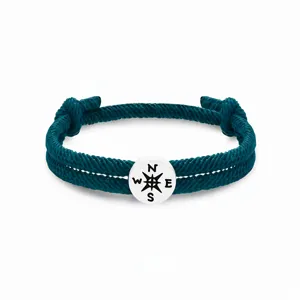 Detailansicht des dunklen türkisen geflochtenen Seilarmbands mit weißem Kompass-Anhänger.