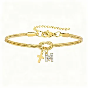 Vista dettagliata del bracciale in catena a serpente dorata con nodo, lettera M e croce.
