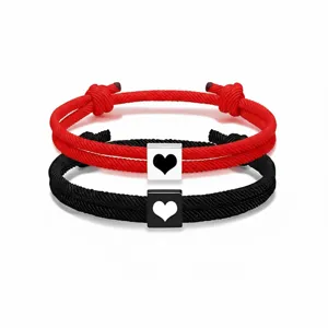 Primer plano detallado de pulseras de cuerda trenzada para parejas con dijes de corazones.