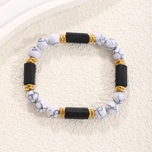 Detailed view of white stone and black bead bracelet with gold spacers for women and men fashion.