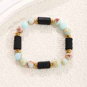 Detailed view of a stylish beaded bracelet with colorful stones, black blocks and gold spacers.