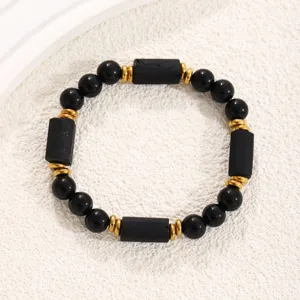 Black and gold beaded bracelet, obsidian cylindrical stones with metal spacers.