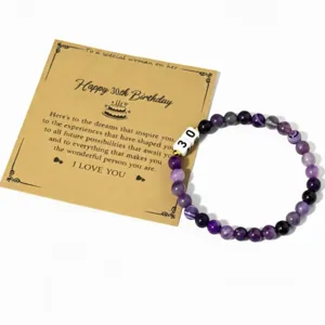 Primer plano detallado de pulsera de cuentas de gema morada con tarjeta de cumpleaños.