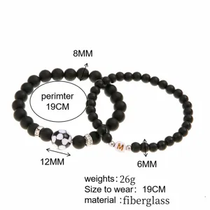 Vista dettagliata dei ciondoli a forma di calcio e lettera M su bracciali di perle nere opache