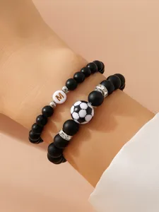 Dettaglio bracciale in perle nere opache con pallone da calcio e iniziale M d'oro