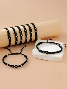 Dettaglio di braccialetti fatti a mano in cordino nero intrecciato con perle argento e lettere