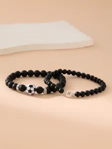 Dettaglio di bracciali in perle nere opache con pallone e lettera H