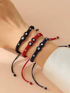 Dettaglio di tre braccialetti intrecciati a mano con lettere M e perle a cuore