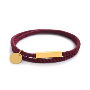 Vista di dettaglio ravvicinata del bracciale in corda bordeaux con una barra metallica dorata.