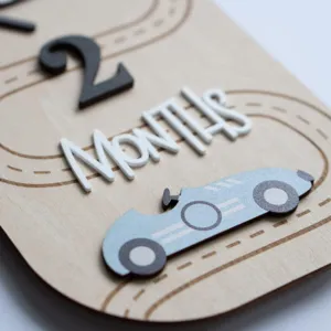Detailed close-up of a wooden baby milestone plaque with 3D number and race car design.