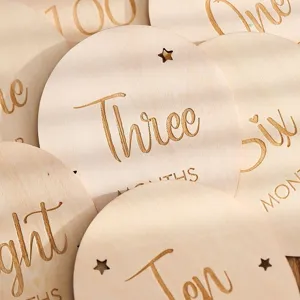 Engraved wooden baby milestone discs for tracking monthly growth and newborn memories.