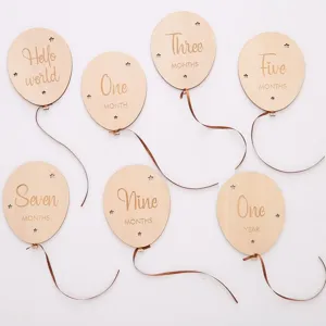 Wooden balloon baby milestone prop detail, natural wood texture with engraved month text.