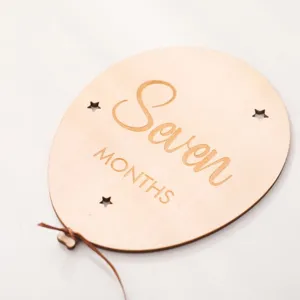 Close-up of wooden balloon baby milestone plaque with engraved lettering and stars. detail shot
