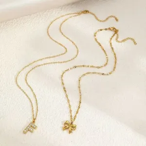 Collana multistrato dorata con ciondolo lettera F in strass e grazioso dettaglio a fiocco.