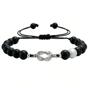 Detail shot of a couple love knot bracelet featuring matte black beads and a unique white bead.