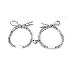 Paar magnetische Herz Armband Set mit grauem gewebtem Seil und Edelstahlanhängern.