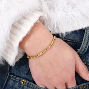 Close-up detail shot of a gold-colored Morse code bead bracelet with adjustable wax rope on wrist.