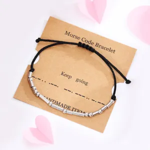Adjustable wax cord Morse code bracelet with silver metal beads on a kraft paper backing card.