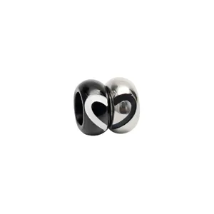 Dettaglio charm cuore in acciaio inossidabile, componente gioiello di coppia abbinato.
