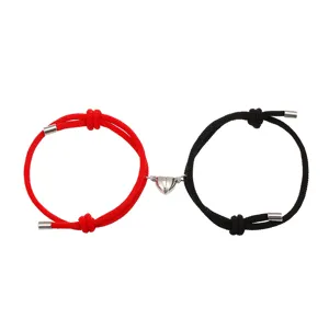 Detailshot van koppel magnetische hart armbanden, rode en zwarte gevlochten touw sieraden.