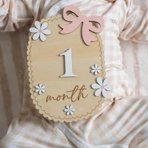 Detailed view of a wooden '1 month' baby milestone card featuring cute daisy accents