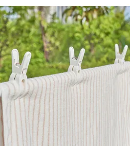 Gros plan détaillé de pinces à linge en plastique blanc avec un ressort coupe-vent très solide.