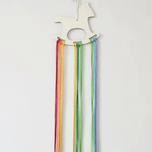 Nordic style wooden rocking horse wall hanging with colorful yarn tassels for hair clip storage.