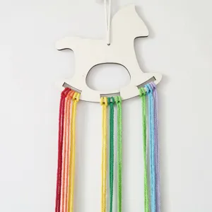 Wooden rocking horse hair clip holder detail, cute nursery wall hanging with colorful yarn.