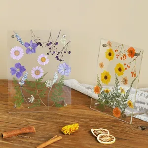 Transparant acryl dubbelzijdig fotolijstje met natuurlijke gedroogde bloemen in detail.