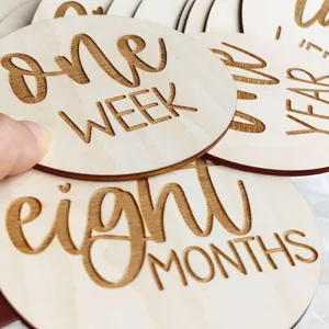 Wooden baby milestone card detail shot, laser engraved weekly and monthly growth photo prop.