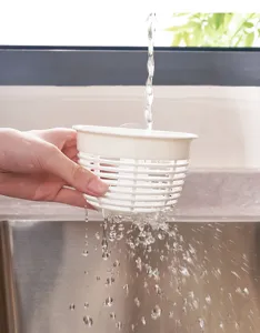 Detailed view of the white plastic sink draining basket being rinsed under running water.