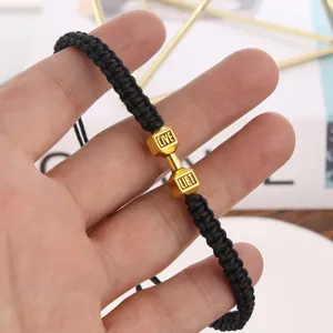 Dettaglio in primo piano del bracciale uomo in corda nera con ciondolo manubrio dorato.