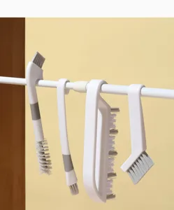 Detail view of versatile Japanese style cleaning brushes hanging on a rod for kitchen gaps.