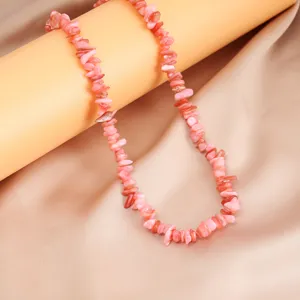 Primo piano dettagliato di una collana artigianale di pietre naturali rosa irregolari.