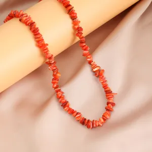 Vista dettagliata di una collana da donna fatta a mano con pietre irregolari rosse estive.