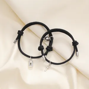 Detail shot of black braided couple magnetic attraction bracelets with lock and key charms.
