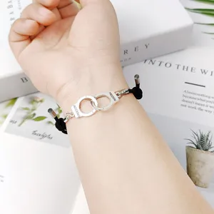 Gros plan détaillé du bracelet en corde noire avec un charm menotte magnétique élégant.