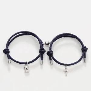 Close-up of matching couple bracelets with lock key charms and magnetic attraction design.