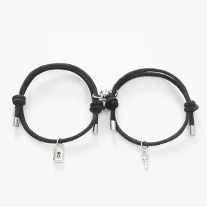 Close-up detail of magnetic couple bracelets featuring lock and key pendants on black cord.