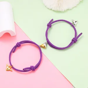 Couple magnetic attraction woven bracelet set detail showcasing the metal heart charms and purple rope.