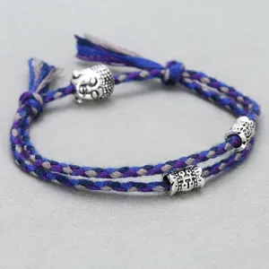 Close-up detail of the braided cotton rope bracelet with metal Buddha head bead and charms.