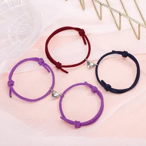 Detailed close-up of matching couple magnetic braided bracelets with cute alloy heart charms.
