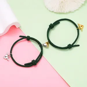 Close-up detail of magnetic couple bracelet with green woven rope and cute winged heart charms.